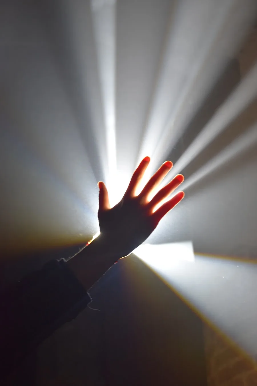A hand reaching into a beam of warm light