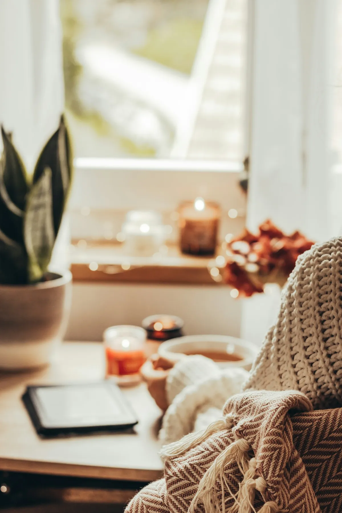 A tablet on a cozy windowsill with tea and candles
